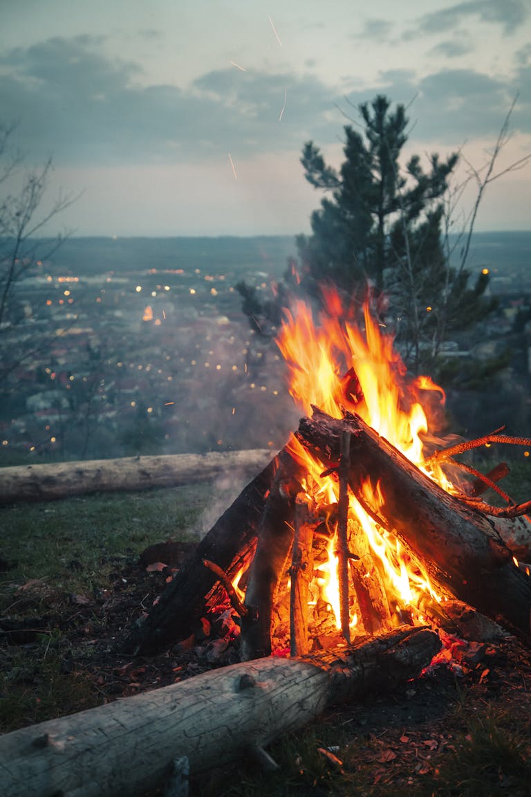 Photo of Bonfire Placed on High Ground in Front of City Under Cloudy Sky